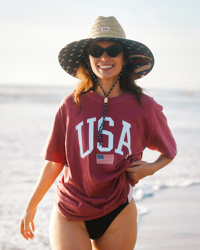 Hemlock female model wearing the UPF50+ Lifeguard Straw Hat Stars & Stripes print by the ocean