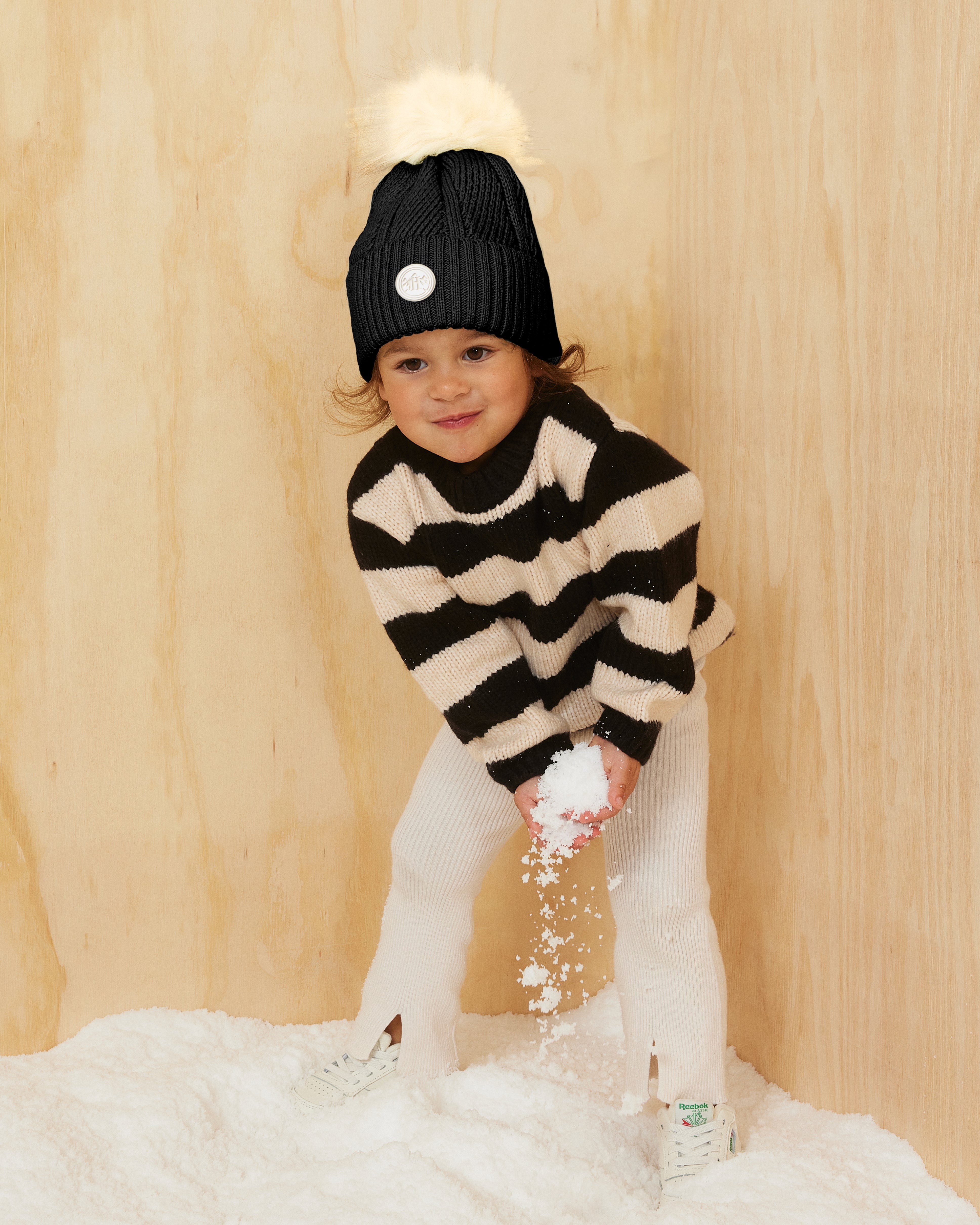 Hemlock baby girl model wearing the  Baby Willow Pom Beanie with white pom