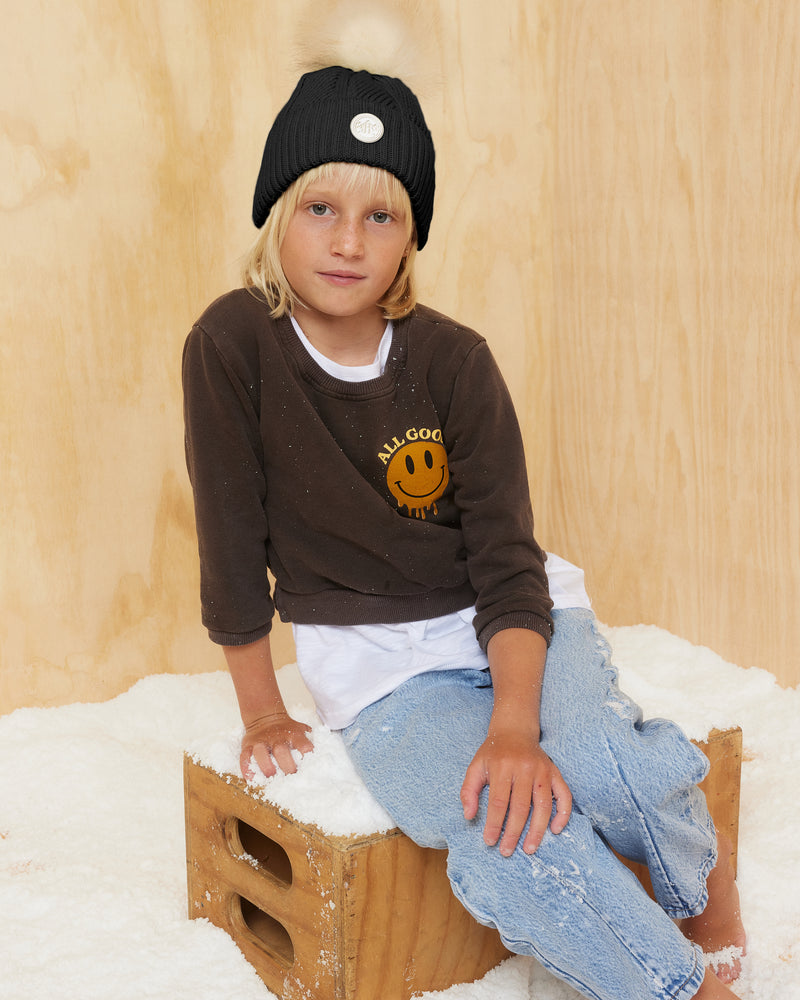 Hemlock little girl model wearing the  Toddler Willow Pom Beanie in Black with white pom