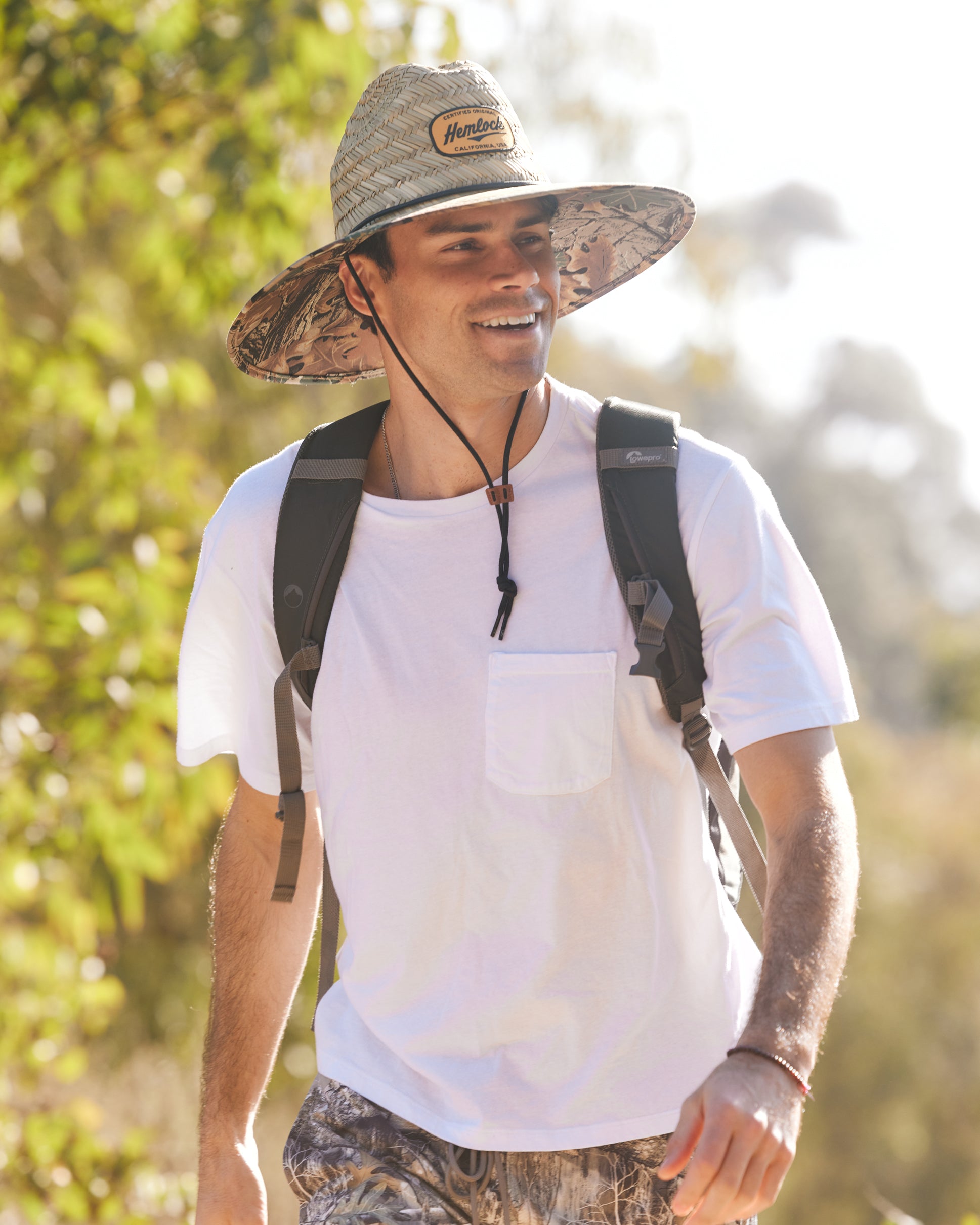 Hemlock male model hiking and wearing the UPF50+ Lifeguard Straw Hat Realtree® Advantage Camo print