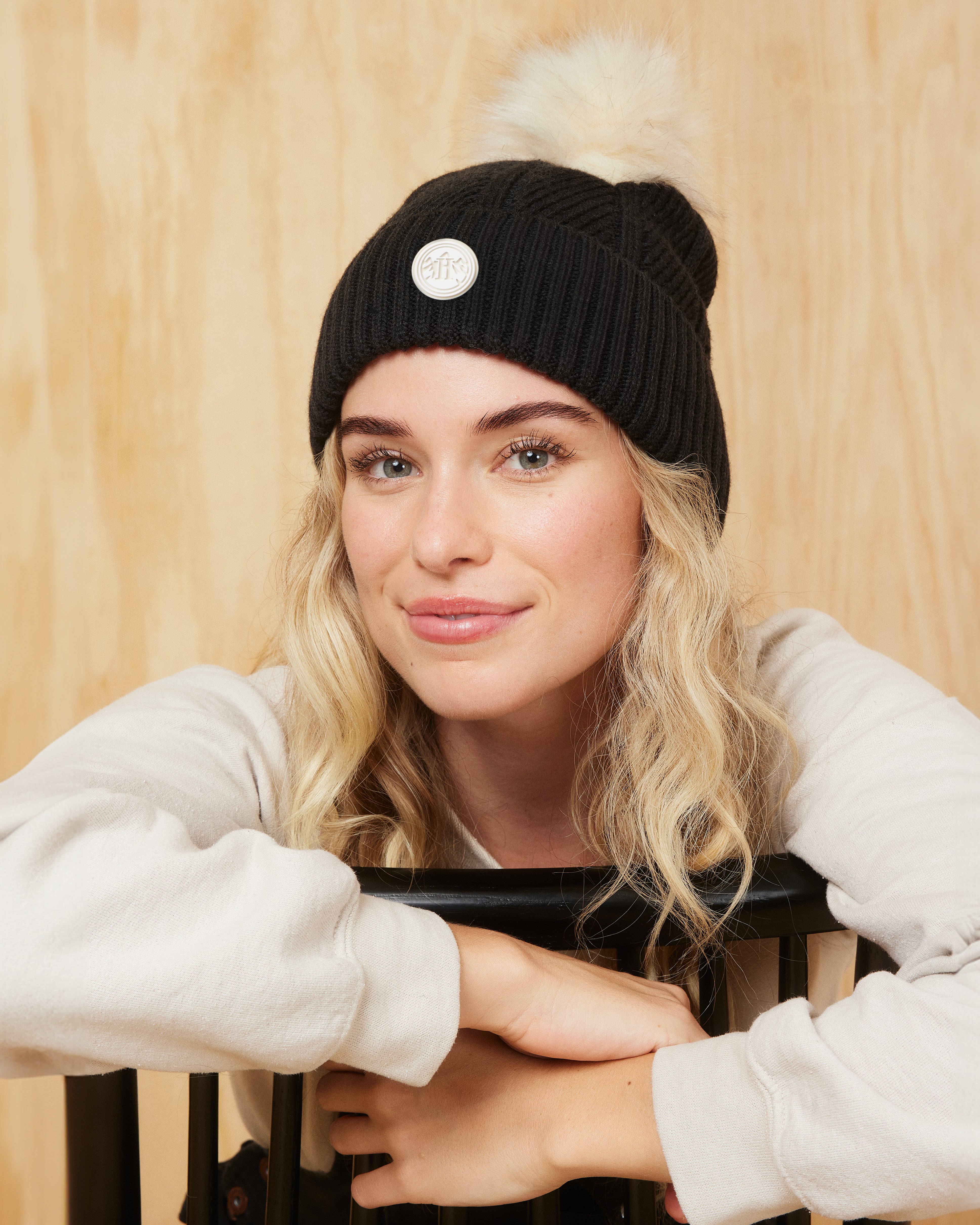 Hemlock female model smiling wearing the Willow Pom beanie in Black with White Pom 