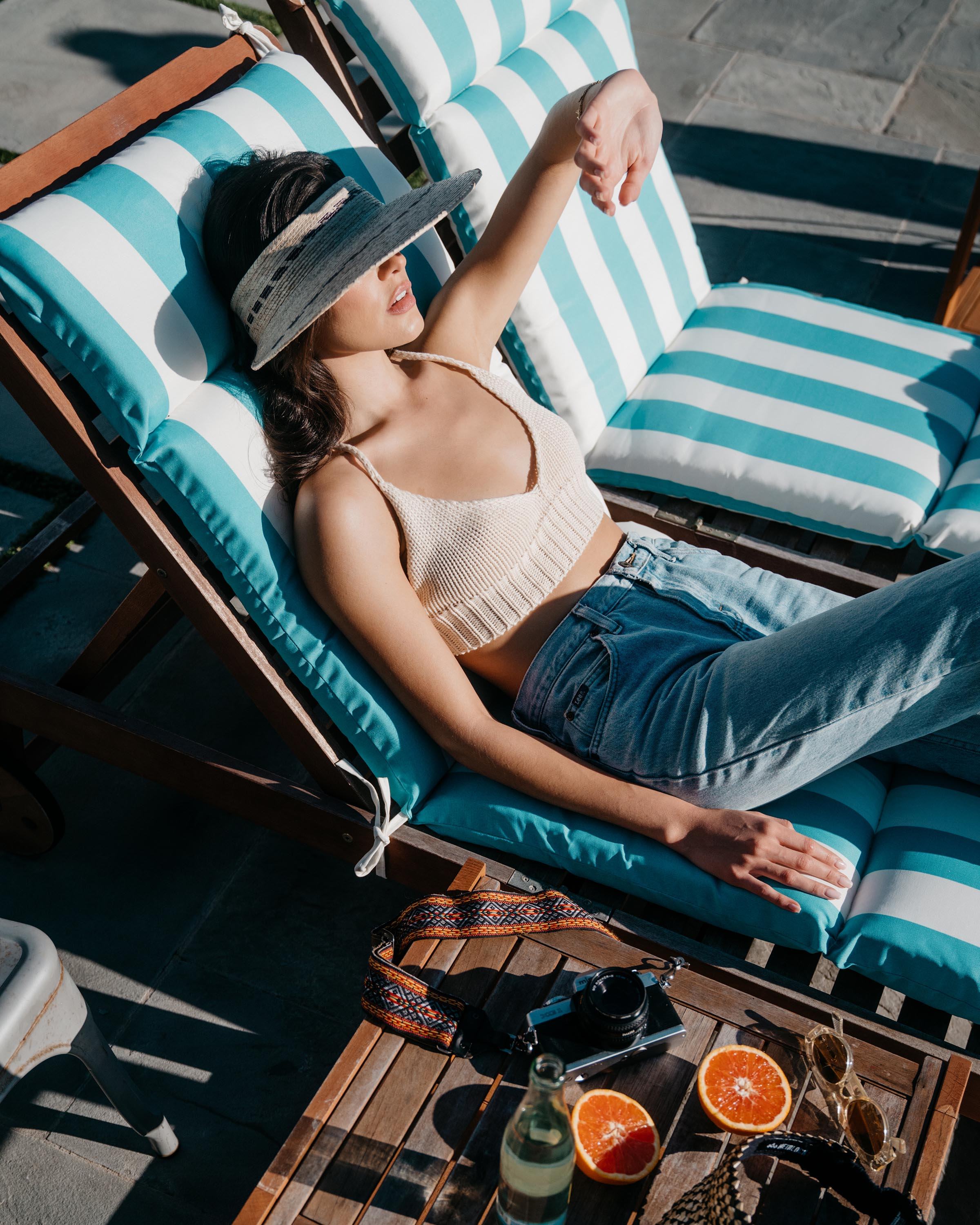 Hemlock female model laying down wearing Catalina Straw Visor in Natural