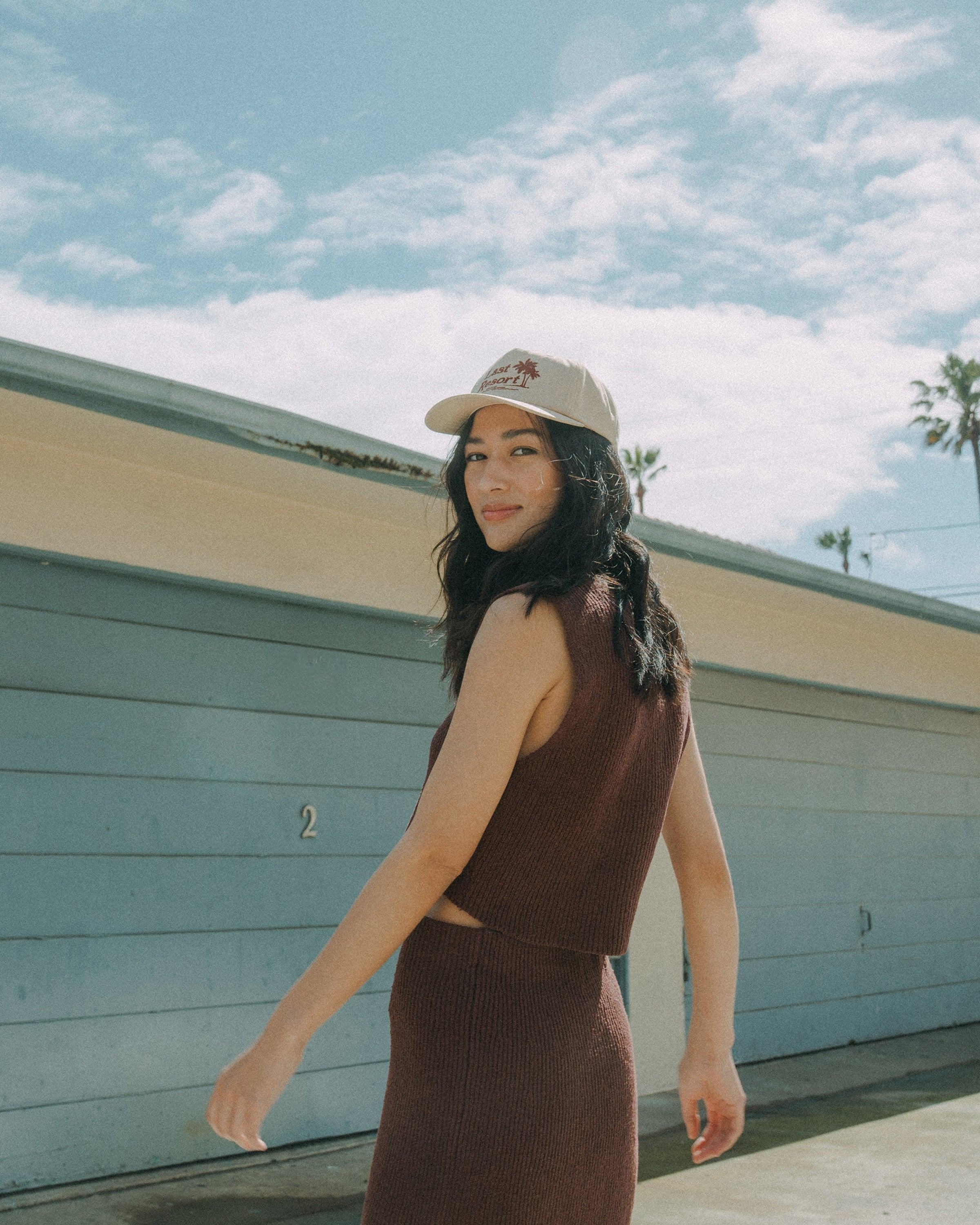 Hemlock female model looking over her shoulder wearing Last resort Baseball Hat in Khaki